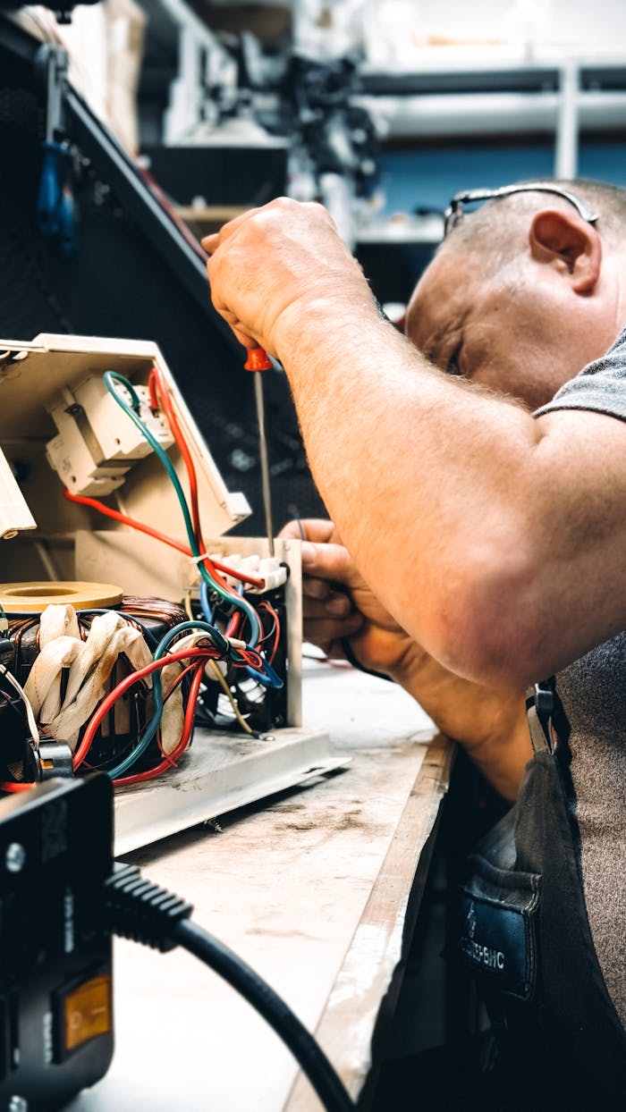 Expert electrician repairing an electrical device in a workshop setting, focusing on wiring.