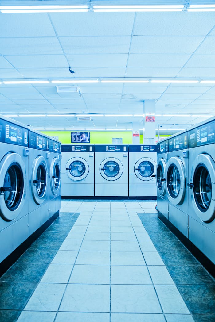 A row of modern washing machines in a brightly lit laundromat in Los Angeles.
