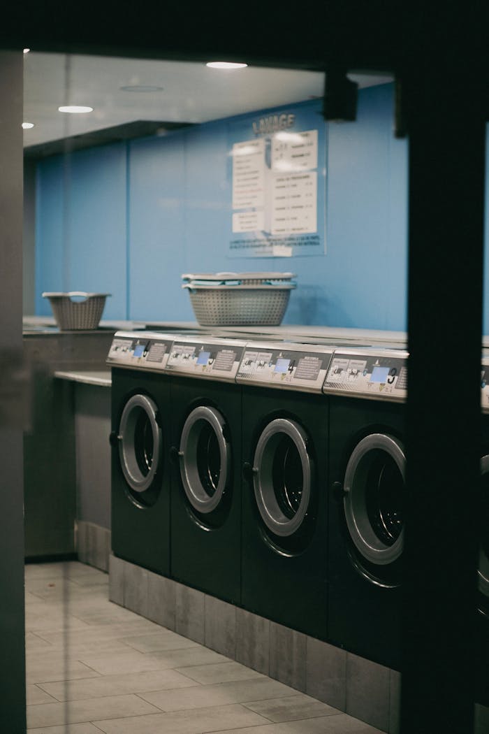 Interior view of a modern laundromat with multiple washing machines lined up.